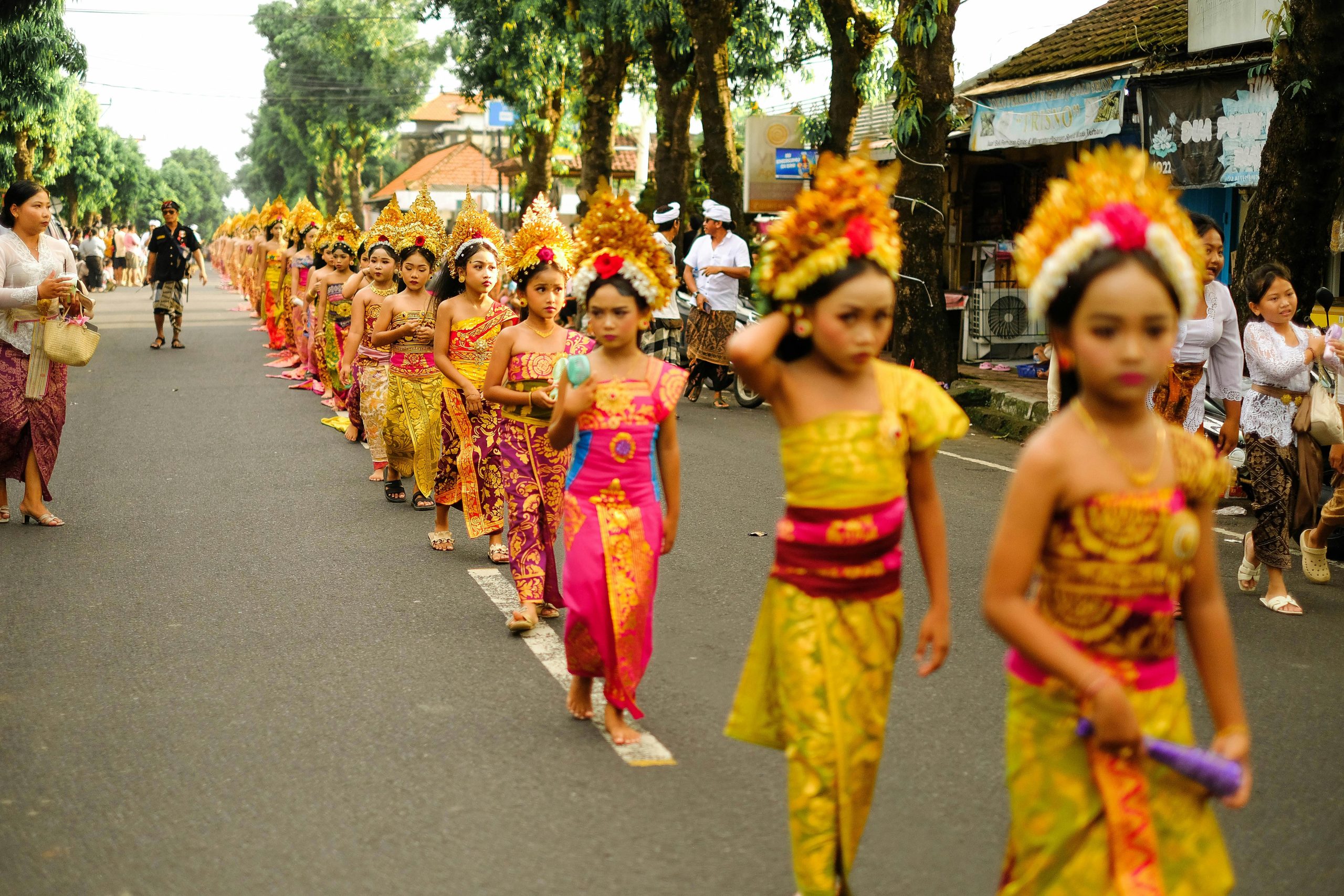 Vibrant cultural parade in Bali, showcasing children in traditional attire on a sunny day.